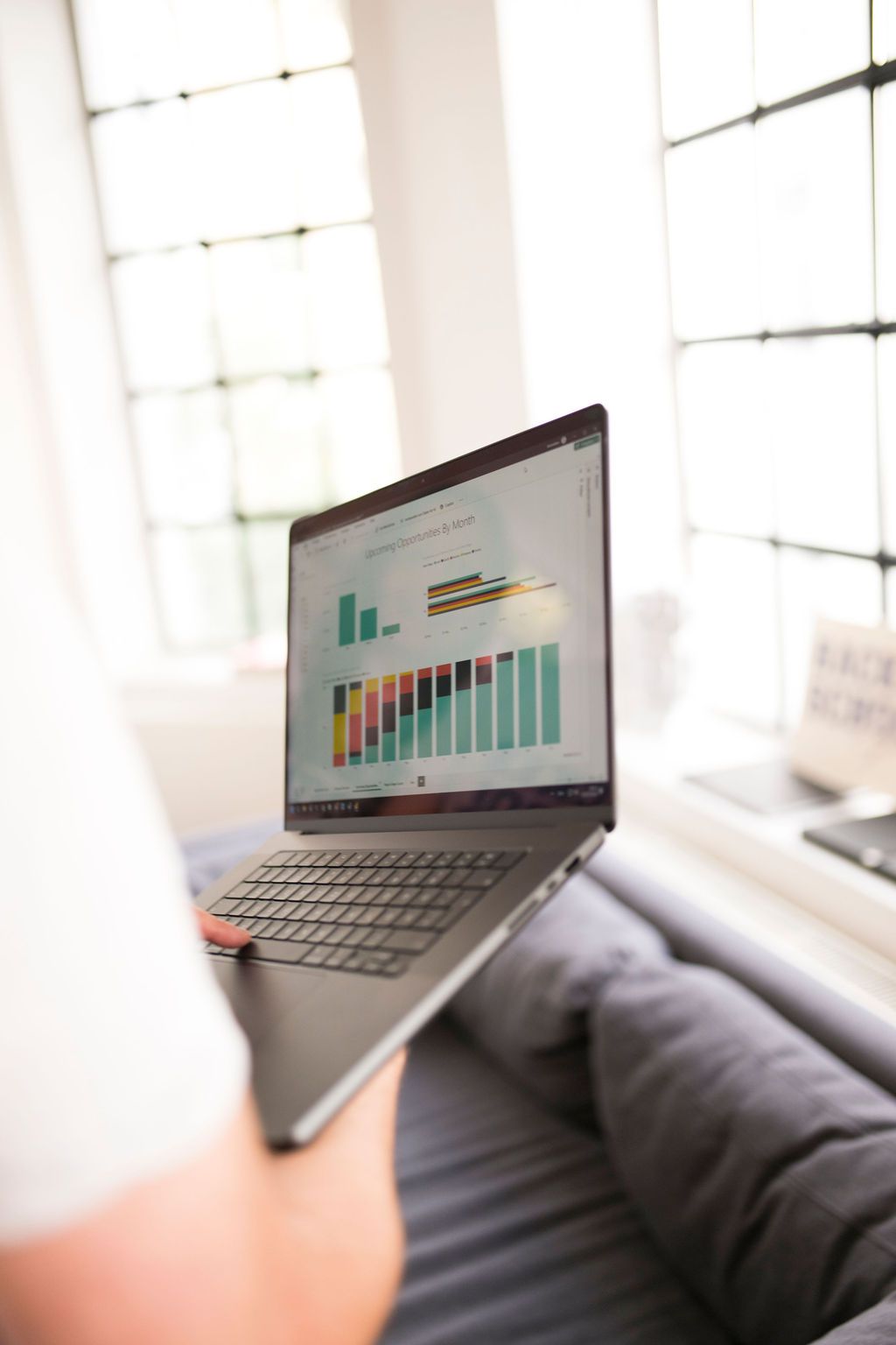 Laptop on a lap showing an outlook for the coming months as a stacked bar chart