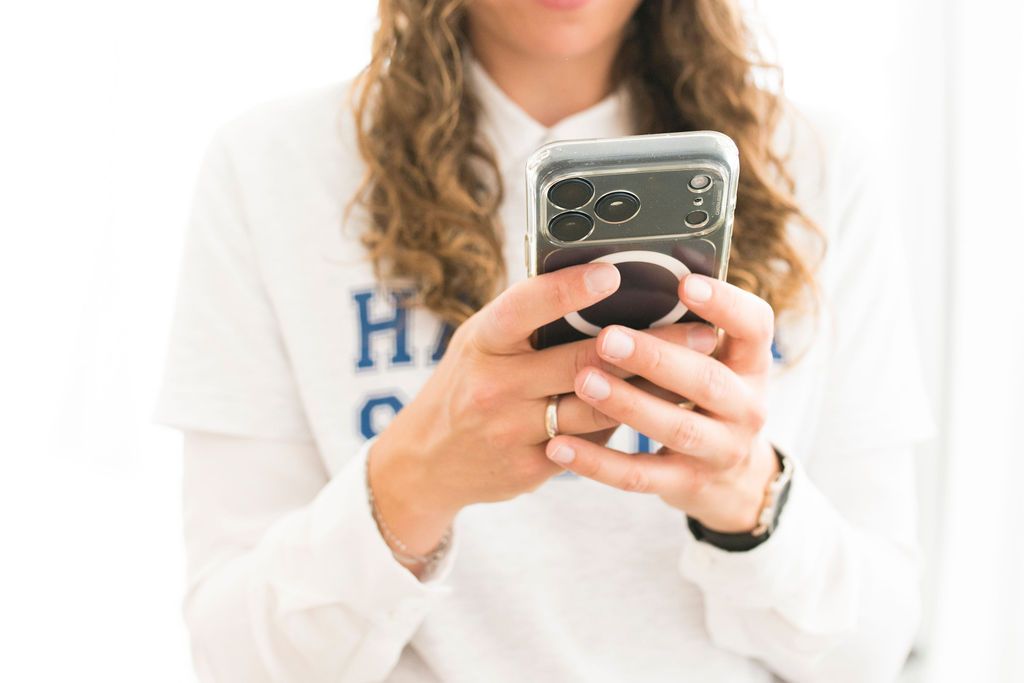 Person in a Hacker School sweatshirt typing on a smartphone